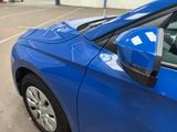 a blue car parked in a parking lot next to a building