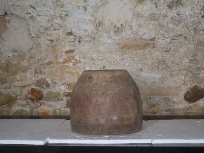 un grand vase en pierre posé sur une table devant un mur de briques