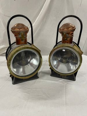 une paire de lampes de chemin de fer anciennes, posées sur des supports, sur un tissu blanc