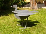 a metal bird that is standing in the grass