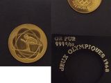 deux pièces d'or sur lesquelles figure le logo des Jeux Olympiques