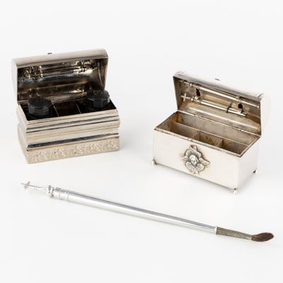two silver boxes and a brush sitting on a white surface