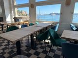 tables and chairs in a room with a view of a body of water