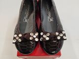 une paire de chaussures noires ornées de nœuds, posée sur une boîte rouge
