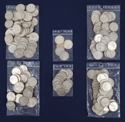 four bags filled with silver coins sitting on top of a blue surface