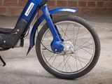 a blue motorcycle parked in front of a brick wall