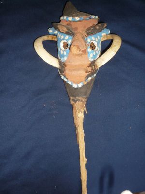 un bâton en bois surmonté d'un masque, posé sur une table