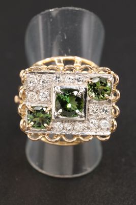 un gros plan d'une bague sertie de diamants verts et blancs