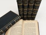 several old books are stacked on top of each other on a white surface
