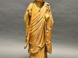 a gold statue of a person standing on a wooden base