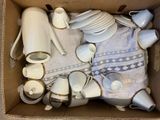 a cardboard box filled with a lot of white and gold items