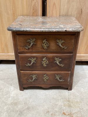 une commode en bois avec un plateau en marbre et des poignées en laiton
