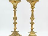 pair of antique brass candlesticks on pedestals on a white background
