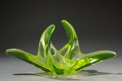 a green glass flower that is sitting on a table