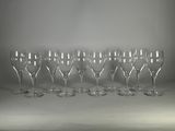 six verres à vin vides sont alignés sur une surface blanche