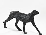 a statue of a dog that is standing on a white surface