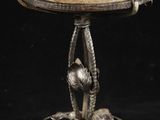 un plat ancien en argent orné d'un oiseau, posé sur un socle