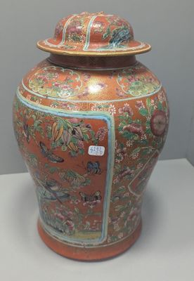 a large orange vase with a lid sitting on a table