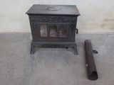 a small stove sitting next to a pipe on the floor
