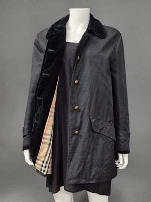un manteau noir avec un col en fourrure et une écharpe à carreaux
