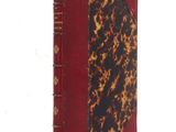 an old book with a red cover sitting on top of a white table