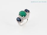 a close up of a ring with a green stone and blue sapphires