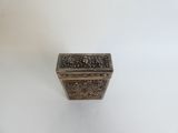 a small silver box with a design on the lid