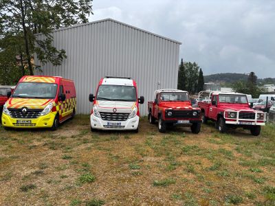 Quatre camions sont garés devant un immeuble aux murs blancs.