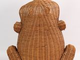 a brown rattan sitting on the floor with its legs crossed