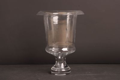un vase en verre contenant une bougie, posé sur une table