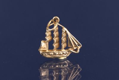 une image représentant un pendentif en forme de voilier plaqué or sur un fond noir