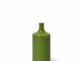 the small green bottle is sitting on a white surface