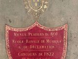 a plaque on the side of a building with a crown on top of it
