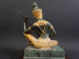 statue of a woman sitting on a rock holding a rifle