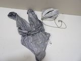 un body argenté posé sur une table, à côté d'un sac à main
