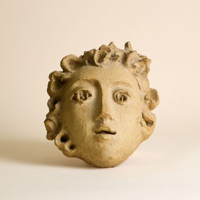 une statue représentant le visage d'un homme sur une surface blanche