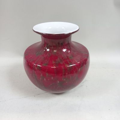 un vase rouge posé sur une table blanche