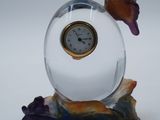 une petite horloge en verre posée sur un rocher