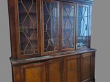 an old wooden china cabinet with glass doors on top of it