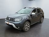 La Dacia grise est garée dans un showroom où il y a une horloge accrochée au mur.