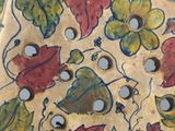 a close up of a decorative plate with flowers and leaves on it