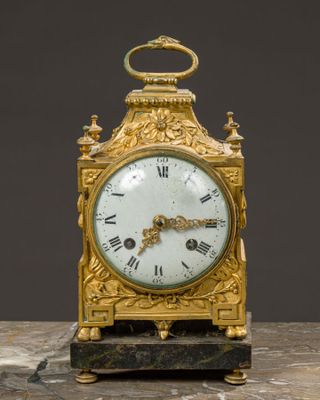 a gold clock sitting on top of a marble table