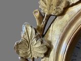 a gold clock with a leaf decoration on it