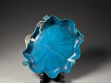 a close up of a blue plate on a stand on a gray surface