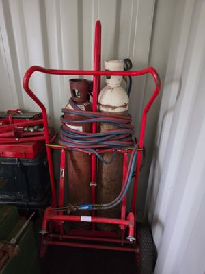 un chariot rouge sur lequel sont empilées de nombreuses bouteilles de gaz