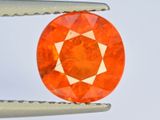 une image montrant un gros plan d'un diamant orange, avec une paire de pinces devant