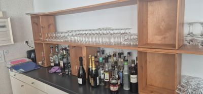 bottles and glasses are lined up on a shelf in a kitchen