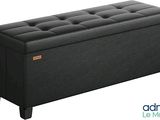 un banc de rangement noir avec un dessus capitonné et des pieds en bois