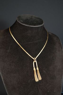 un collier en or orné d'un pompon autour du cou d'un mannequin