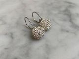a pair of silver earrings sitting on top of a marble counter